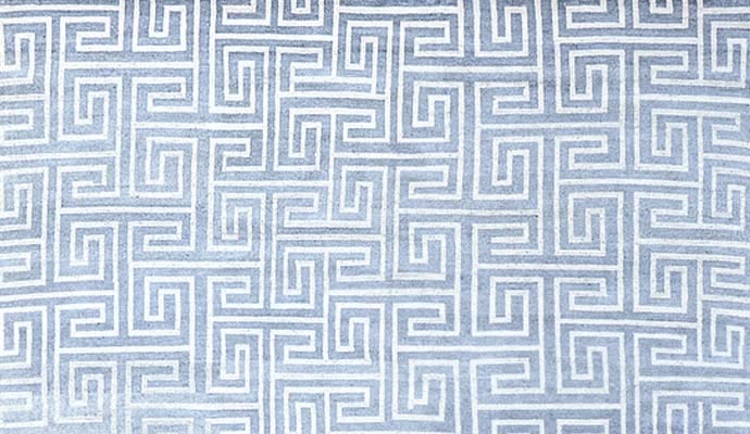 A blue rug has a Greek key pattern.