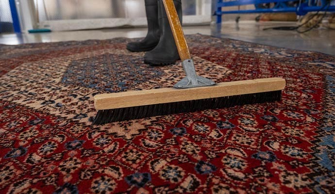 A professional cleaning oriental rug using hand-scrubber