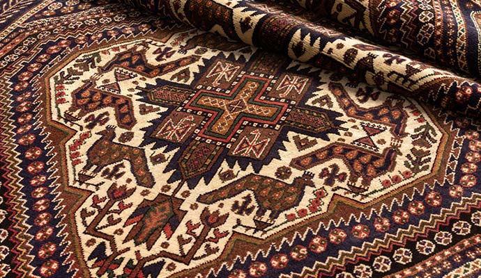 Antique Persian tribal rug with geometric bird motifs and folded corner