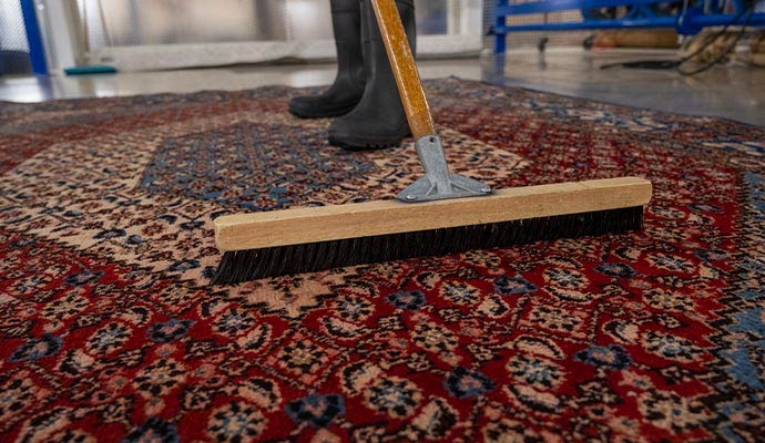 Expert technician using a specialty brush to groom a traditional oriental area rug