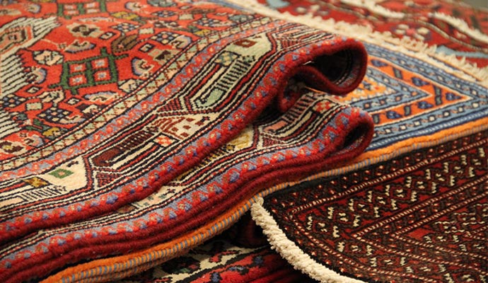 A stack of colorful hand-knotted oriental rugs