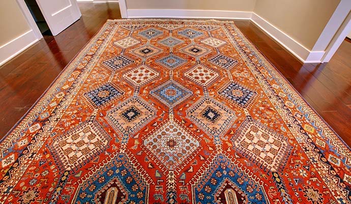 Handmade geometric pattern oriental rug laid out on a dark hardwood floor