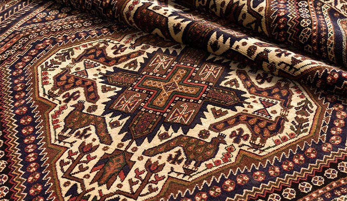 Close-up of a traditional Persian rug with intricate geometric and bird patterns in earth tones