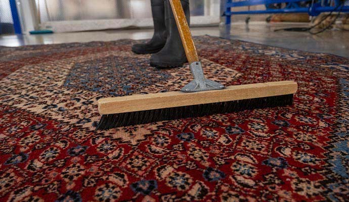 Person cleaning an oriental rug